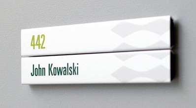 dörrskylt i vitt och gröna detaljer med plats för runsnummer och namn